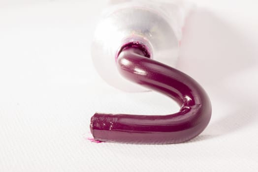 Magenta paste for oil painting is squeezed out of a tube on to a white canvas.