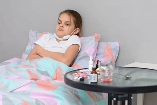 The girl lies in bed and does not want to take medicines