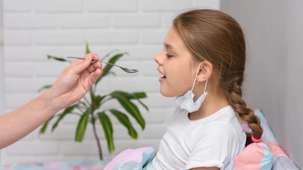 A girl drinks medicine in the hospital