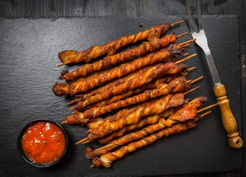 Grill skewer with hot salsa dip on black background