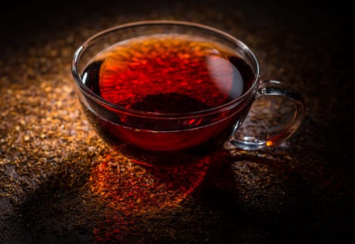 Cup of delicious rooibos tea on dark background