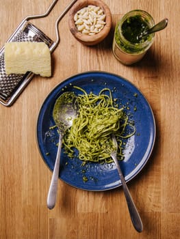Bowl of basil pesto and pasta on an old wood table.