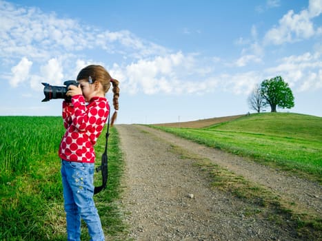 Young girl with a big camera in rural Switzerland taking pictures of the scenery.