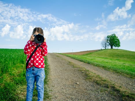 Young girl with a big camera in rural Switzerland taking pictures of the scenery.