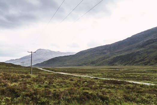 Landscape of mountains, a road and telephone posts in Scotland
