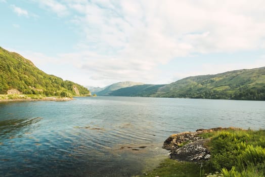 Lake with in Scotland Highlands with calm sea and mountains ashore