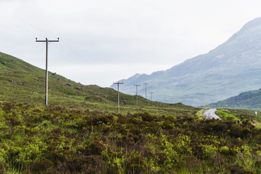 Landscape of mountains, a road and telephone posts in Scotland