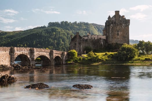 Old castle with a bridge with arcs and a river in a sunny day in Scotland, Eilean Donan Castle