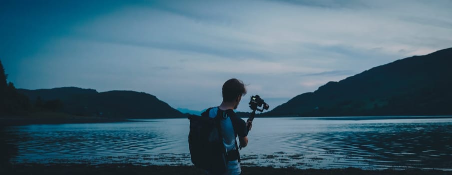 Person using a camera to film and shoot a lake in Scotland during sunset