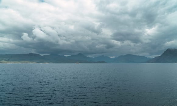 Lake with a boat in Scotland Highlands with calm sea and mountains ashore