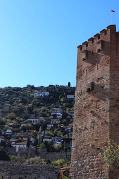 Bedesten Alanya fortress. Big red bricks tower with residential buildings on background. Turkey.