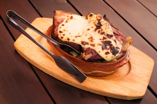 Served baked pork knuckle with cheese sauce on table.