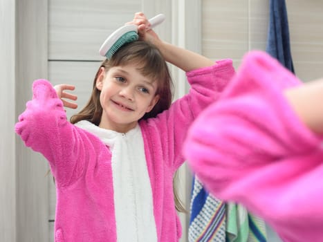 Girl combing her hair in the bathroom early in the morning