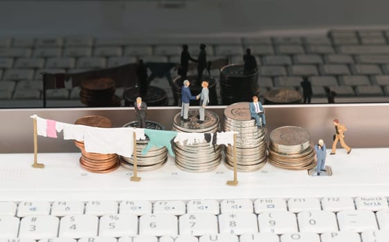 Money laundering concept with miniature people, clothesline and coins on top of a notebook