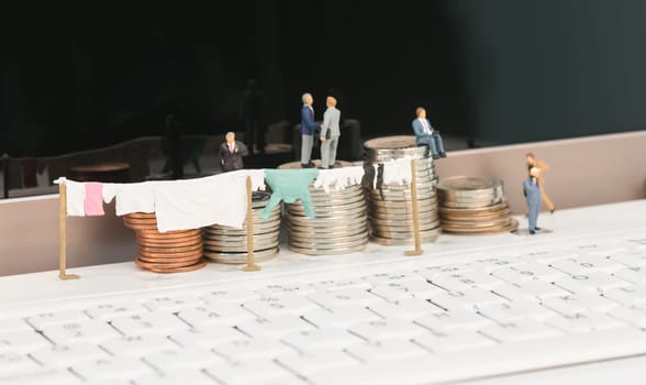 Money laundering concept with miniature people, clothesline and coins on top of a notebook