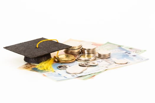 Education costs concept with mortar board and coins on top of banknotes