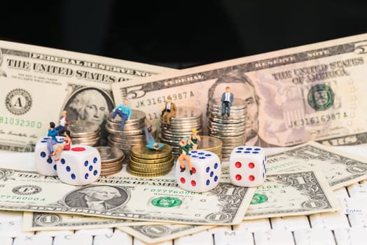 Online gambling concept with miniature people and coins on top of a notebook