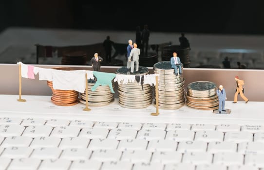 Money laundering concept with miniature people, clothesline and coins on top of a notebook