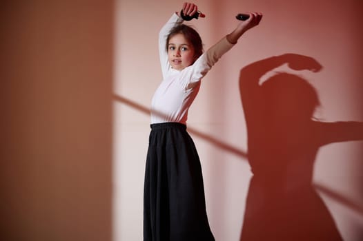 A young girl dances gracefully in an artfully lit environment, showcasing expressive movements and dynamic poses, celebrating creativity and beauty.