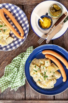 Homemade potato salad and sausages on rustic plates