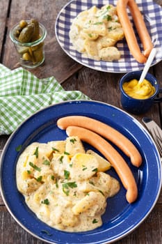 Homemade potato salad and sausages on rustic plates
