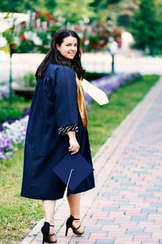 Smiling student woman on graduation day looking at camera. Stepping confidently into the future concept. Focus on her face.