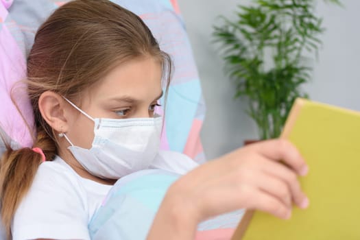 Girl reading a book while lying in bed in a hospital ward