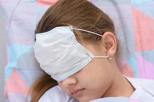 The girl fell asleep in bed, on her face and eyes she pulled on a medical mask, close-up