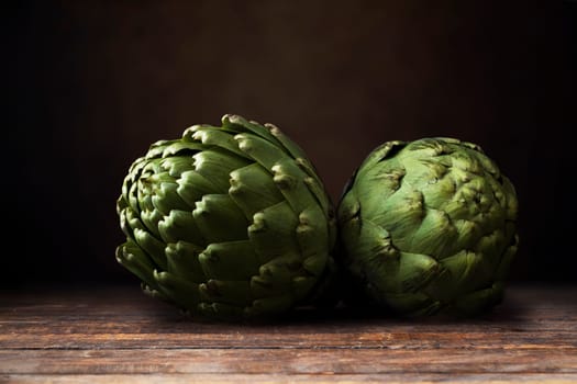 Two artichokes on dark wooden surface