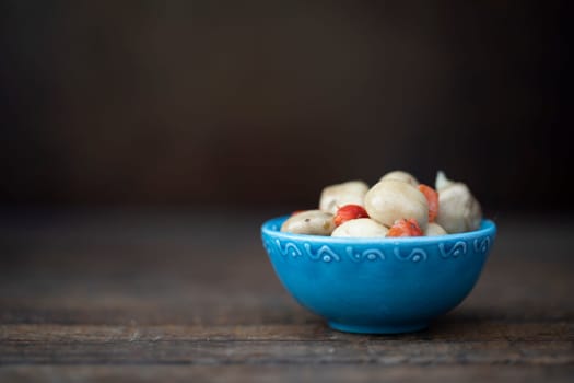 Marinated mushrooms tapas in greek ceramic bowl on wooden tablewith copy space.