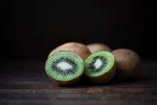 Fresh kiwi on dark wooden table with dark background and copy space.