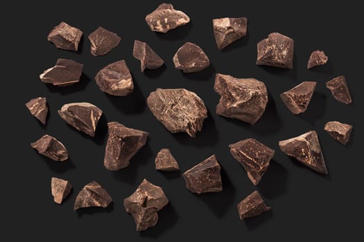 Broken chocolate pieces isolated on black, top view