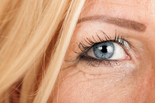Close-up of the right eye of a blonde, blue-eyed middle-aged woman.