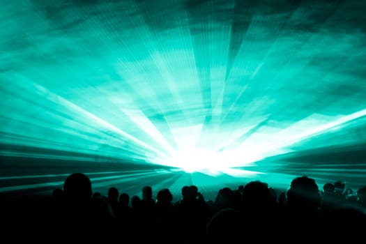 Luxury entertainment with audience silhouettes in nightclub event, festival or New Years Eve. Beams and rays shining colorful lights.