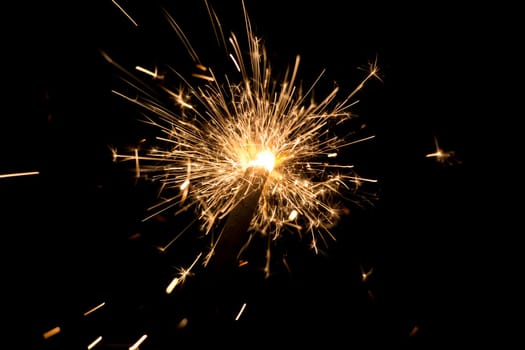 Luxury entertainment at e.g. New Years Eve, Independence Day or birthday party celebration. Glowing light spark on dark background.