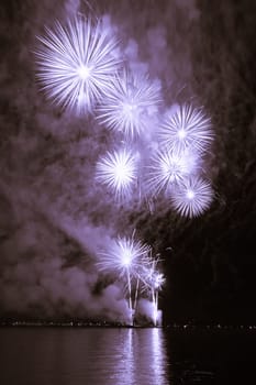 Premium entertainment magic star firework at e.g. New Years Eve or Independence Day party celebration. Nice lake surface reflections.