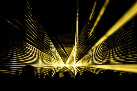 Luxury entertainment with audience silhouettes in nightclub event, festival or New Year's Eve. Beams and rays shining colorful lights.