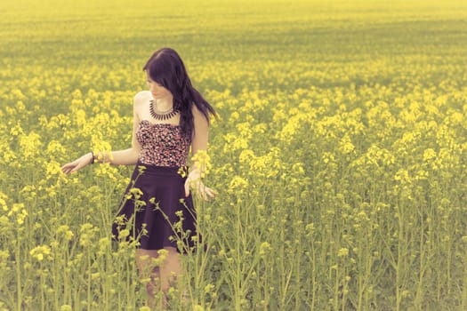 Attractive young beauty girl enjoying the warm sunny sun in nature rapeseed field takes time feeling sustainability and contemplation.