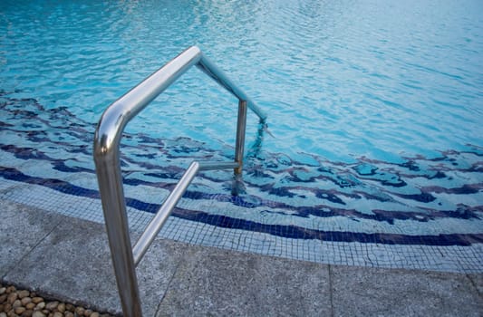 blue swimming pool with teak wood flooring stripes summer vacation