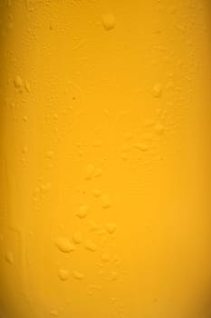 Close-up condensation at a golden beer glass in vertical format