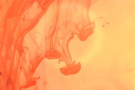 Orange Ink Drops in Water. Liquid Fantasy Art Splashes. Abstract Background.