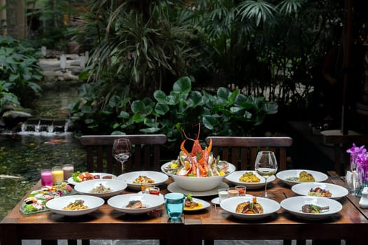 Side view premium variety of international food in garden of restaurant of lobster shrimp steak beef lamb pasta spaghetti risotto rice sushi sashimi and wine using for buffet food drink background.