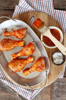 Marinating chicken drumsticks with BBQ sauce and spices