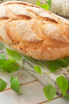 Fresh and delicious bread on wooden shabby cutting board and birch branch for healthy diet concept