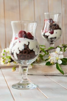 Layered dessert with chocolate cake, whipped cream and raspberry in a jar, spring flowers