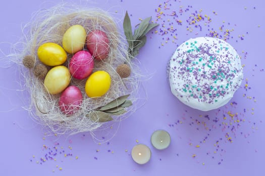 Easter eggs in the nest, cake, candles on a purple background