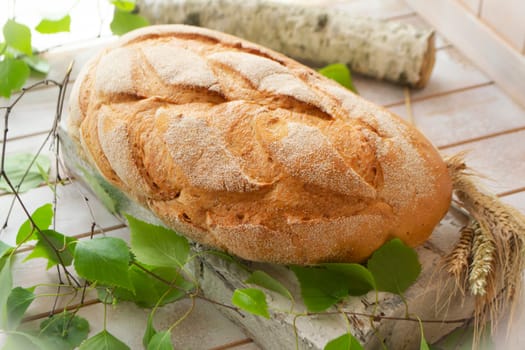 Traditional whole wheat bread on rustic light wooden table with birch branche
