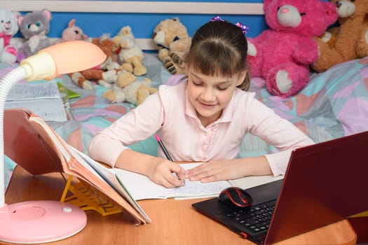 in the children's room sits a girl at a desk and makes a homemade