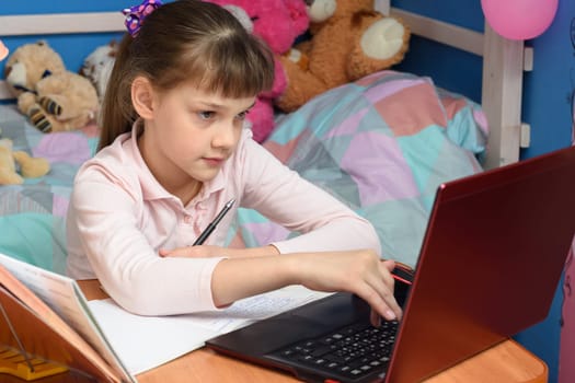 girl in home clothes sits in a room and prints in a laptop