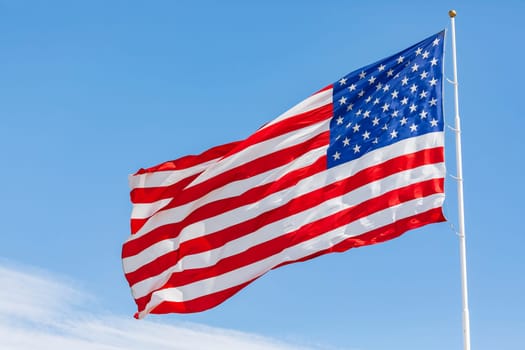 American flag waving in the wind on blue sky, US flag motion close-up, red white blue flag outdoors in sunlight. United States of America national flag. USA stars and stripes